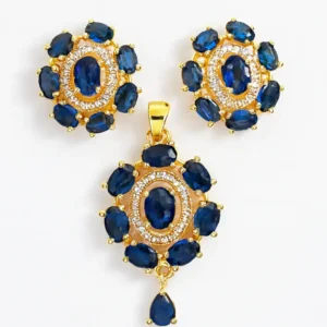 Blue Sapphire-Coloured Stone Gold-Plated Pendant Set with Matching Earrings by Risha Fine Jewels, featuring oval-cut blue stones and CZ crystal halo design, displayed on hand.