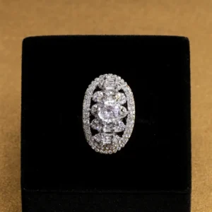 Silver-plated Moonlit Lace Oval CZ Radiance Ring by Risha Fine Jewels featuring an oval-cut center stone, sparkling CZ halo, and intricate lace-pattern band displayed on a blue velvet surface.