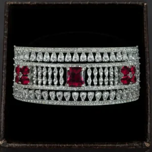 White-gold plated CZ statement bracelet with ruby accents for women by Risha Fine Jewels, featuring wide designer band with sparkling cubic zirconia stones and ruby crystals.